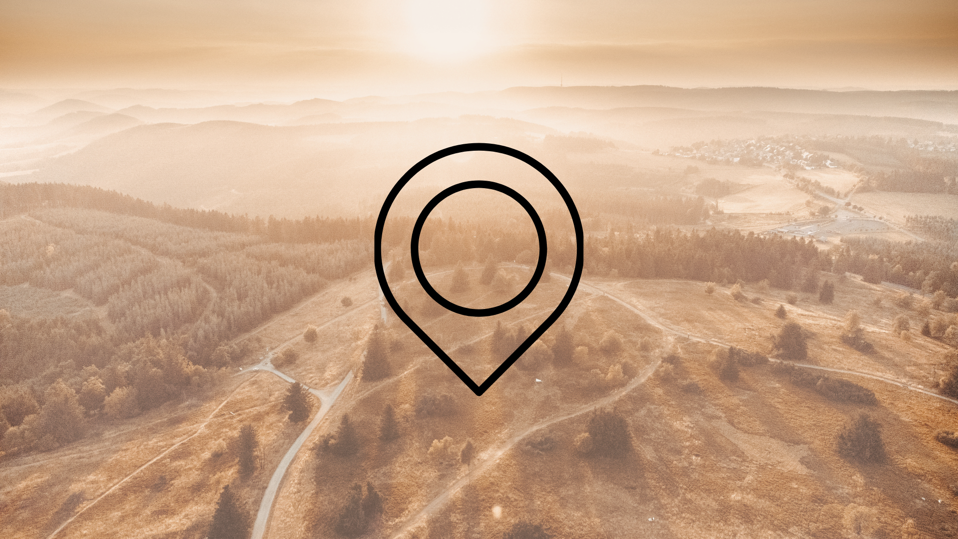 Drohnenaufnahme einer weitläufigen Landschaft mit Wiesen, Feldern und Wäldern und der Zeichnung eines Markierungszeichens im Vordergrund. Dieses Bild gilt als Symbolbild für Sehenswürdigkeiten.