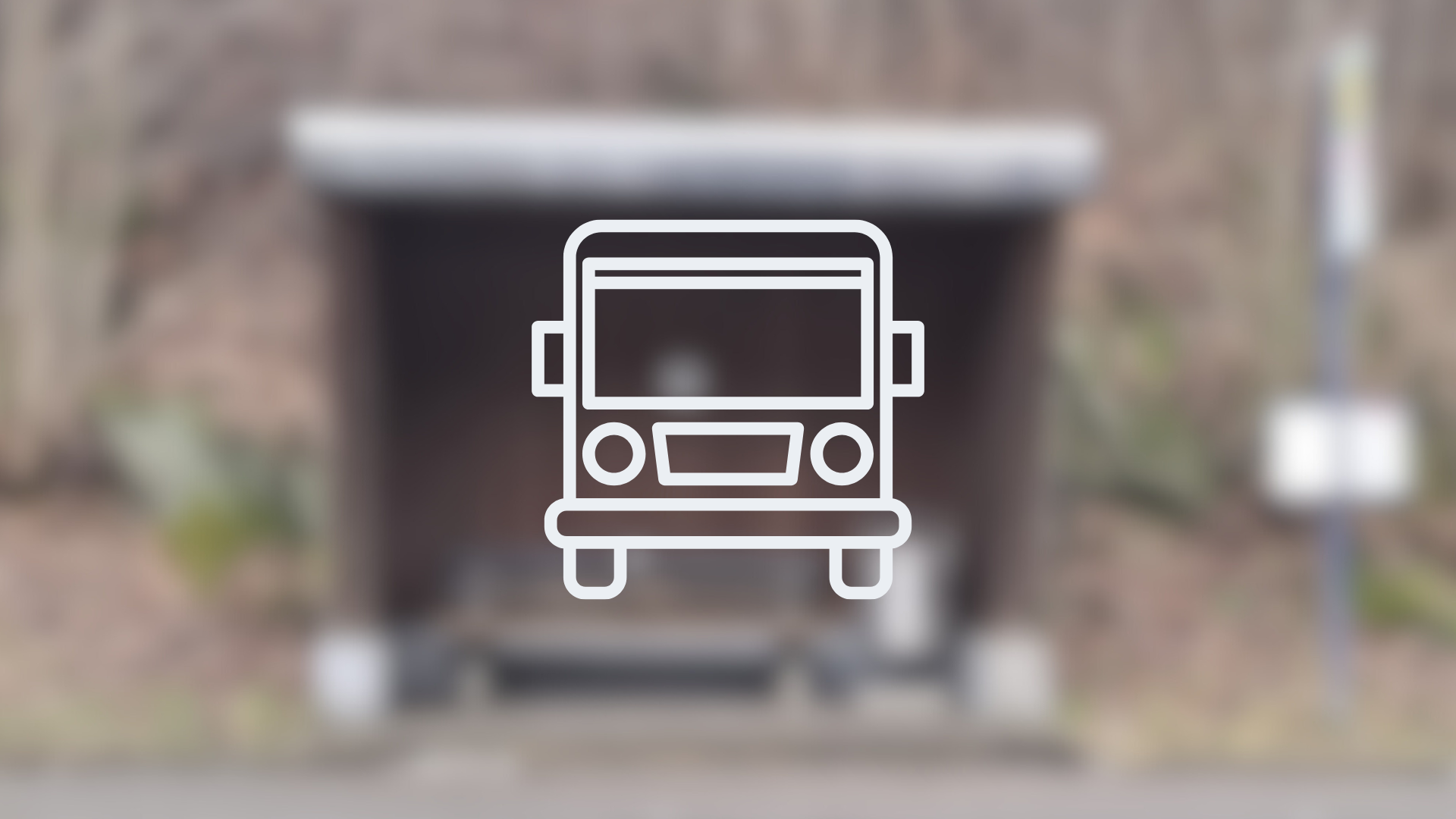 Ein verschwommenes Bild eines Bushaltestellen-Häuschens mit der Zeichnung eines Busses im Vordergrund. Dieses Bild dient als Symbolbild für Bushaltestellen.
