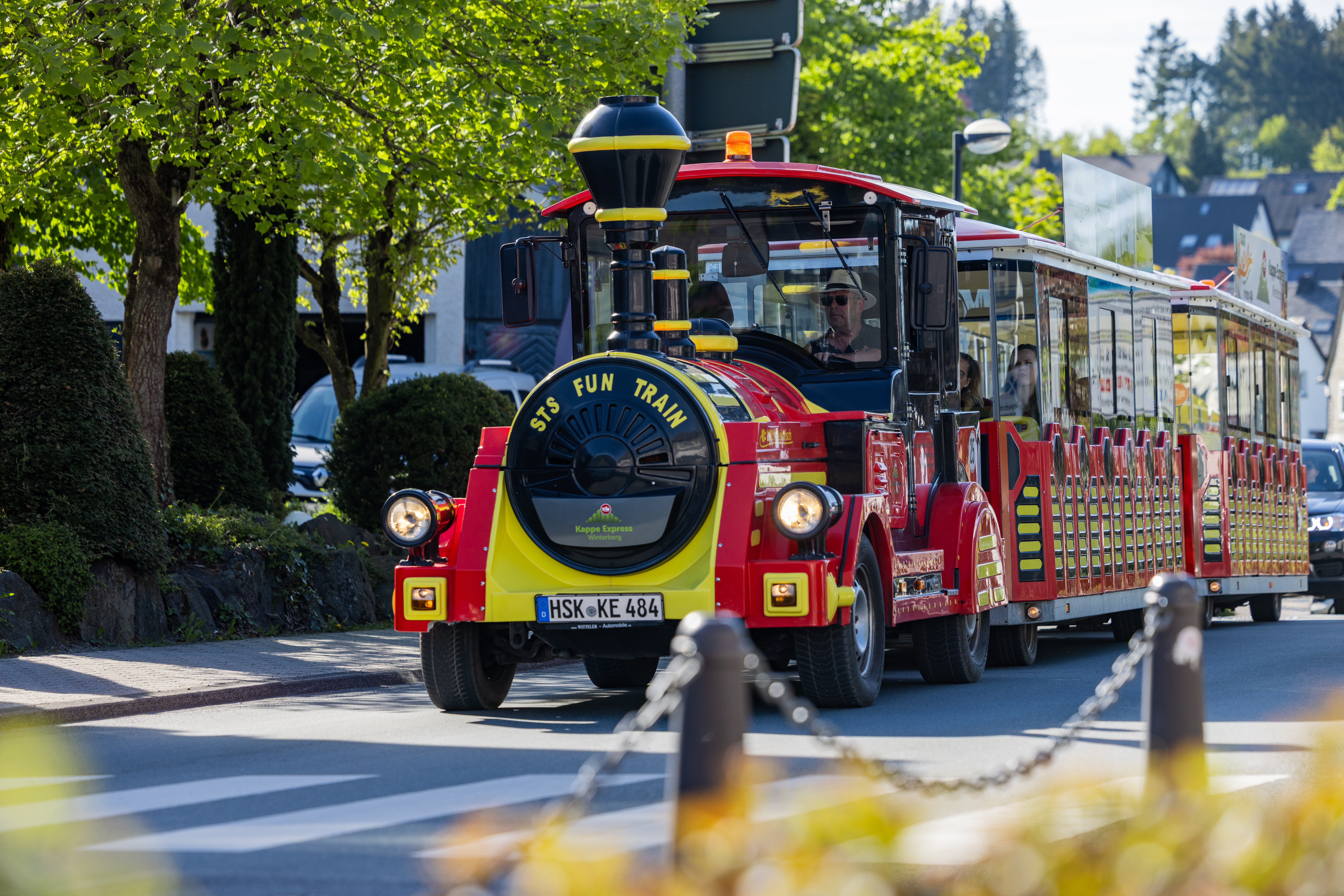 Eine rot-gelbe Eisenbahn fährt die Straße entlang.