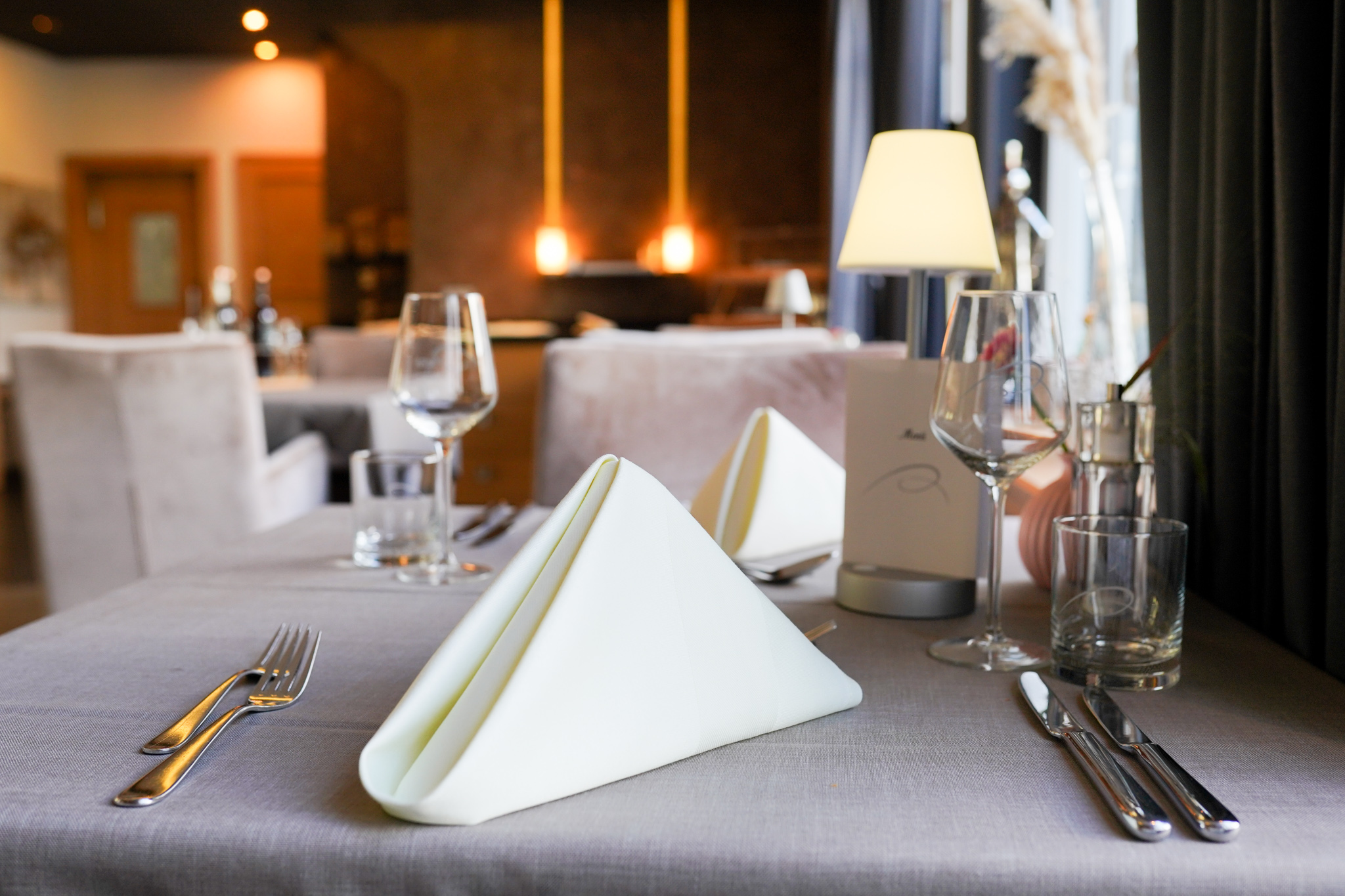 Ein mit gefalteten Servietten und Besteck eingedeckter Tisch in einem Restaurant.