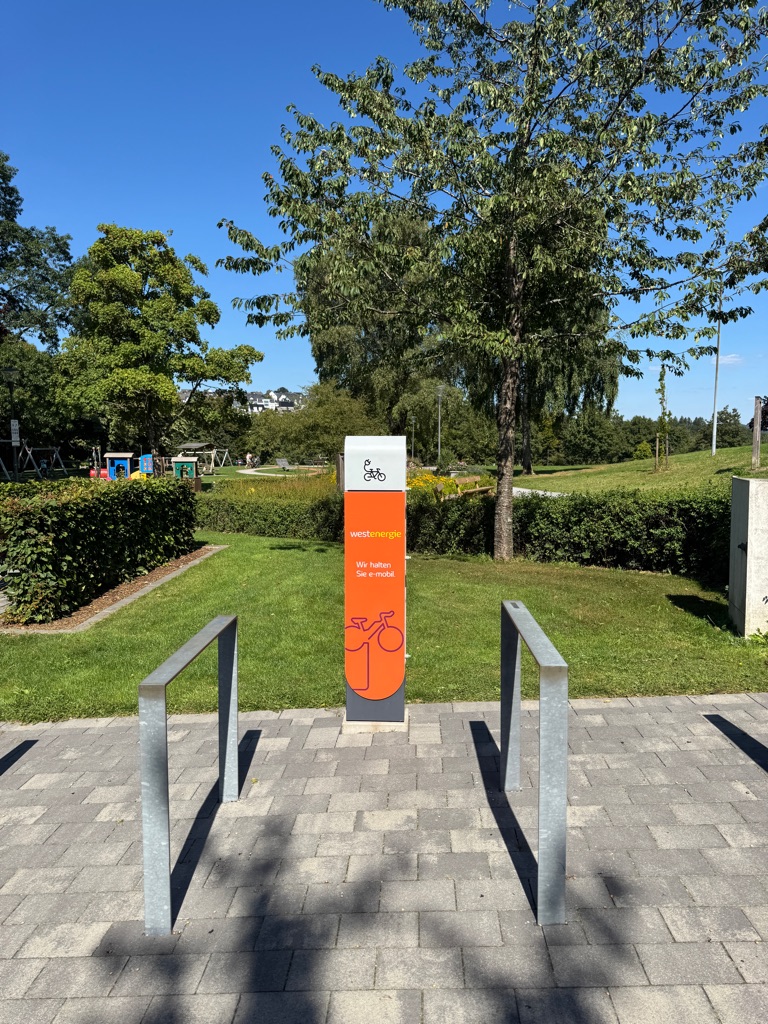 Eine orangefarbene Akku-Ladestation für E-Bikes im Kurpark.