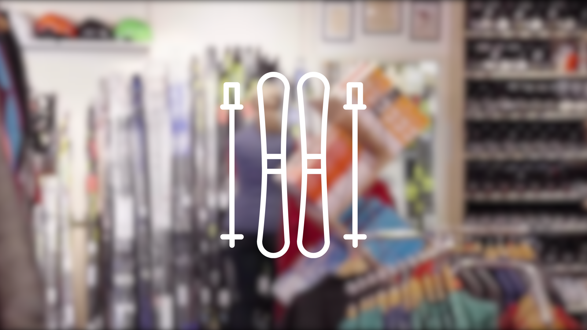 Ein verschwommenes Bild verschiedener Skiausrüstung mit der Zeichnung eines Paar Skiern mit Skistöcken im Vordergrund. Dieses Bild dient als Symbolbild für Skiverleihe.